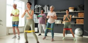 Un groupe d’adultes faisant des exercices avec des bandes de résistance dans un studio lumineux.
