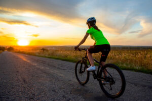 A woman cycling on a dirt road.