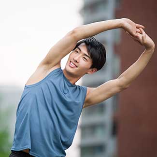young man holding his hands over his head while strech to the side