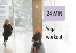 yoga instructor leading seated student in gym