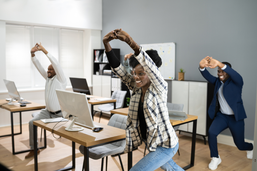 A group of colleagues doing lunges in an office.