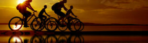 A group of people applying cycling safety tips as they bike at sunset.