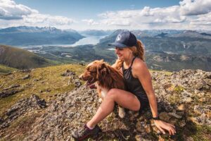 Britt Pearson posing with one of her nine dogs on top of a mountain