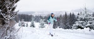 A woman cross-country skiing - a great way to boost your mood- on a nature trail.