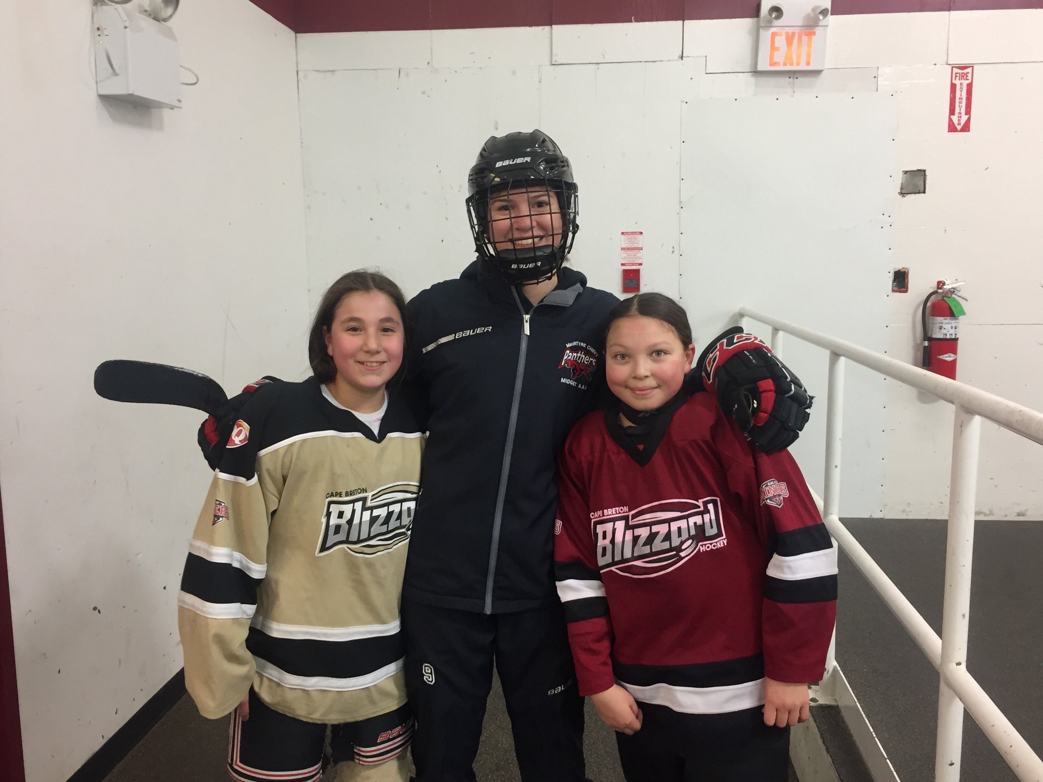 Erin Denny and two hockey players posing for a photo. 