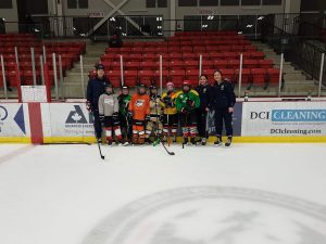 A group of hockey players and coaches at an indoor rink.