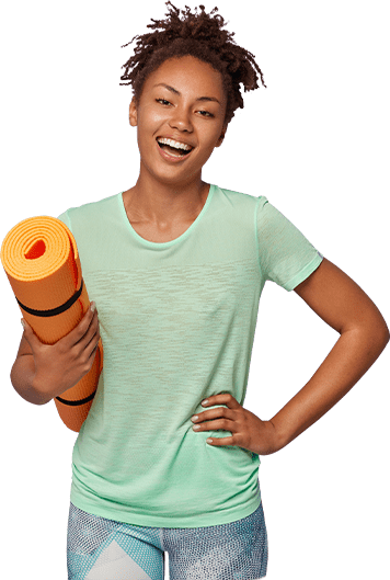 A woman smiling and holding an orange yoga mat