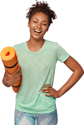 Une femme souriante transporte un tapis de yoga orange