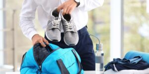 A man putting running shoes in a gym bag. 