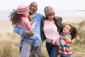 A father, mother and their two children walking on a beach in winter. 