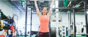 woman overhead presses barbell in gym