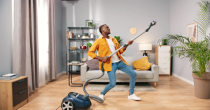 A man playing air guitar using a vacuum cleaner.