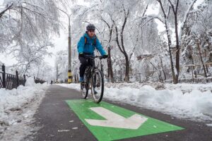 Un homme faisant du vélo sur une piste cyclable en hiver.