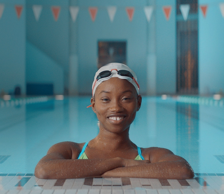 Une adolescente souriante en maillot de bain dans une piscine