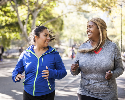 two women smiling and walking briskly in the fall Deux femmes souriantes en train de courir