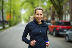A smiling woman jogging on a street. 