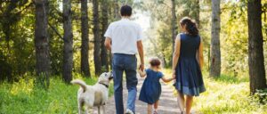 A family walking their dog in summer, one of many healthy summer habits worth keeping up in fall.