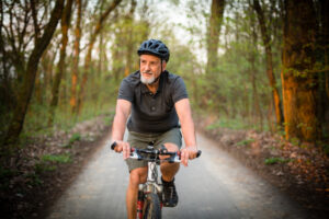 elder man biking in a forest