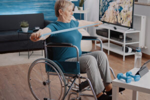 Une femme âgée en fauteuil roulant utilisant une bande de résistance. 