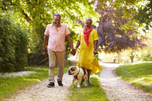 Senior,Couple,Walking,With,Pet,Bulldog,In,Countryside