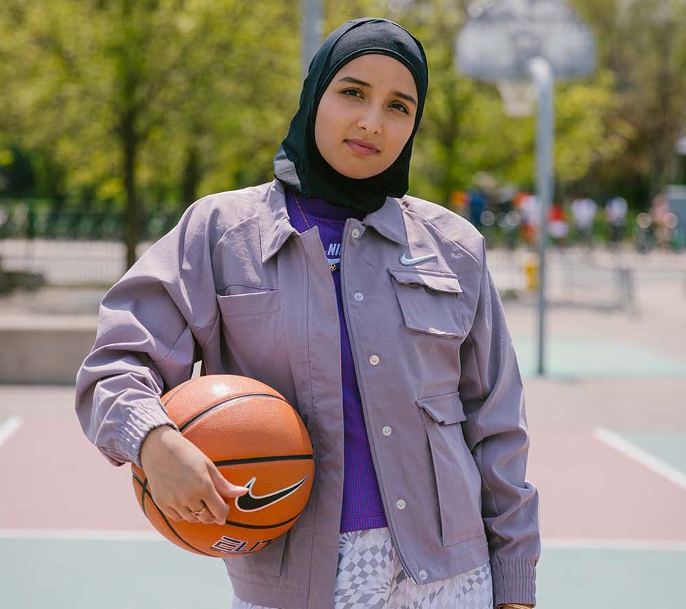 Amreen Kadwa tient sur un terrain de basket tout en tenant un ballon de basket.