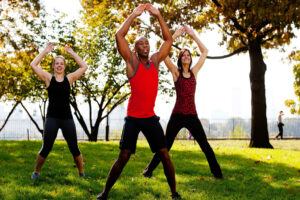 two women and a man exercising in a park