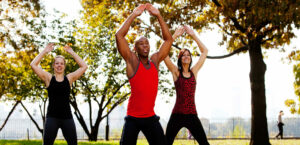 two women and a man exercising in a park