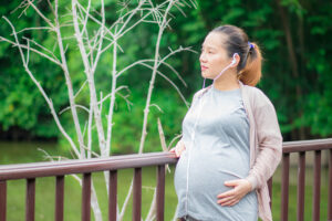 A pregnant woman walking on a bridge over a river