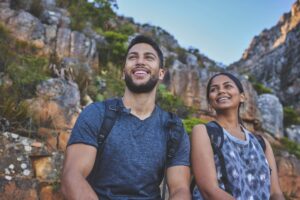 A smiling couple standing in front of a cliff. They get outside regularly.