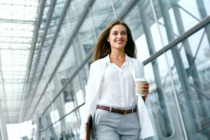 A woman walking while carrying a coffee. 