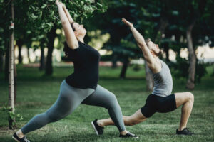 a woman and a man doing yoga in a park