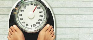 A person standing on a scale because losing weight is one of their goals.