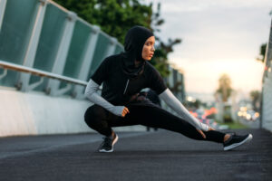 A Muslim woman stretching on running path.