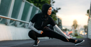 Une femme musulmane s'étire sur une piste de course