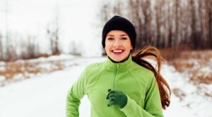 A smiling woman jogging on a snow-covered nature trail. She has learned how to be your best self.