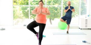 A man and woman doing yoga poses because they learned how to start exercising again after a long break. 