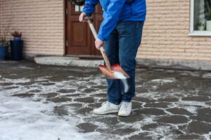 A person shoveling a driveway. 