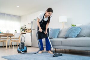 Une femme passant l’aspirateur sur un tapis de salon. 