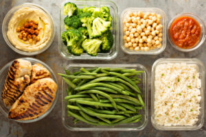 Du houmous, du brocoli, des pois chiches, de la salsa, du poulet grillé, des haricots verts et du riz sur une table. La préparation de repas