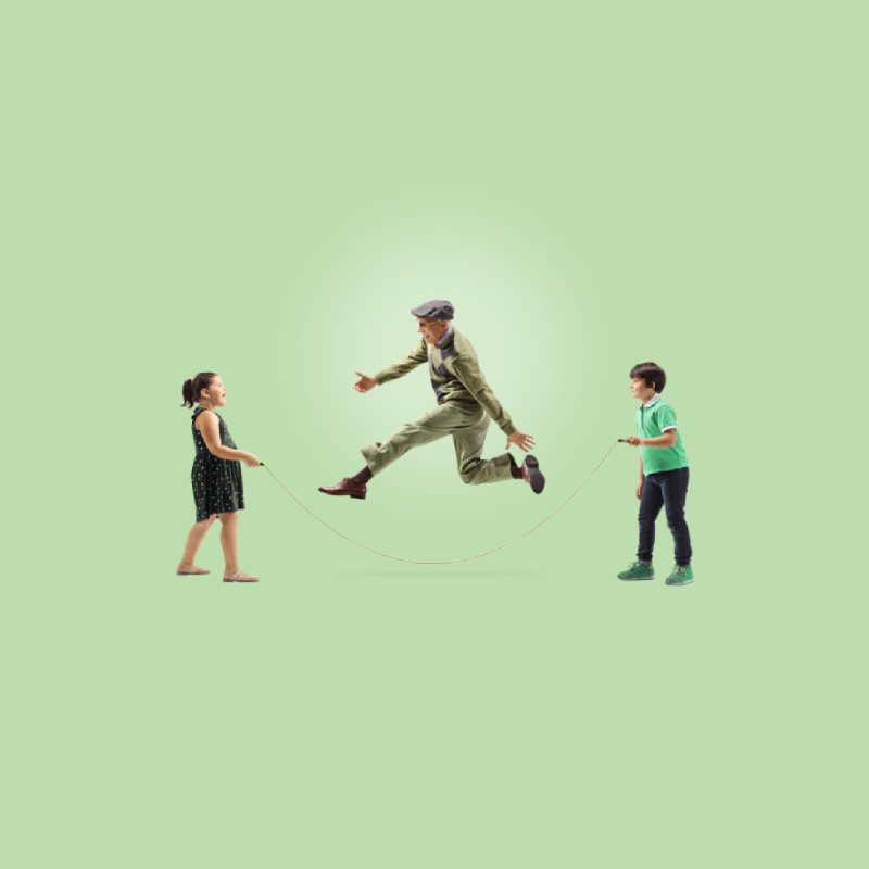 An older man skipping with two children holding the rope