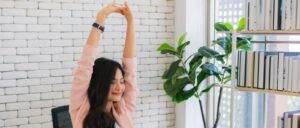 A woman stretching in her office. This is one of many healthy workday habits to form.