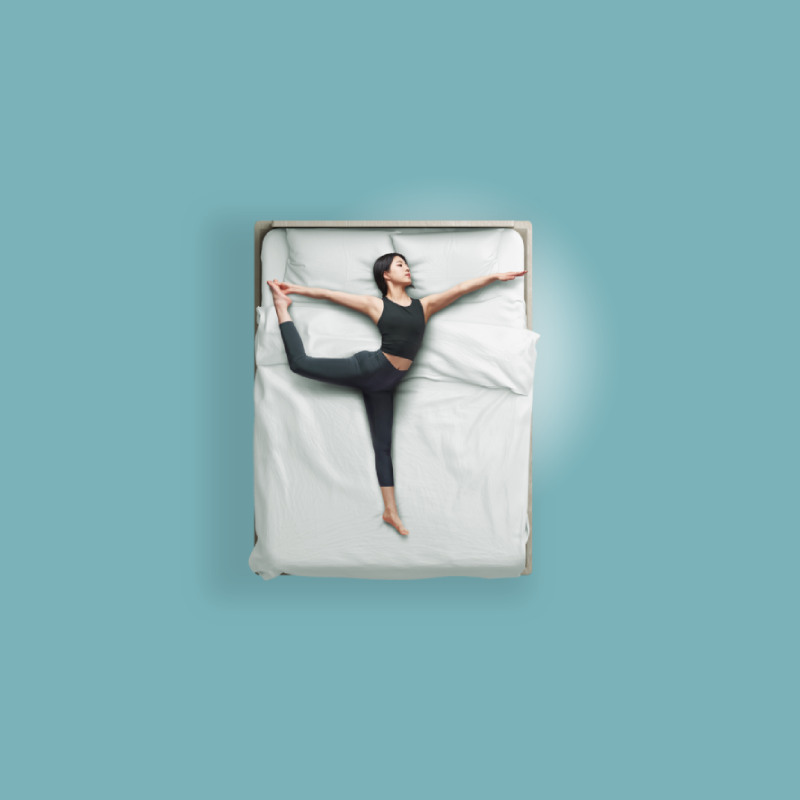 An image of a woman in yoga pose on a bed