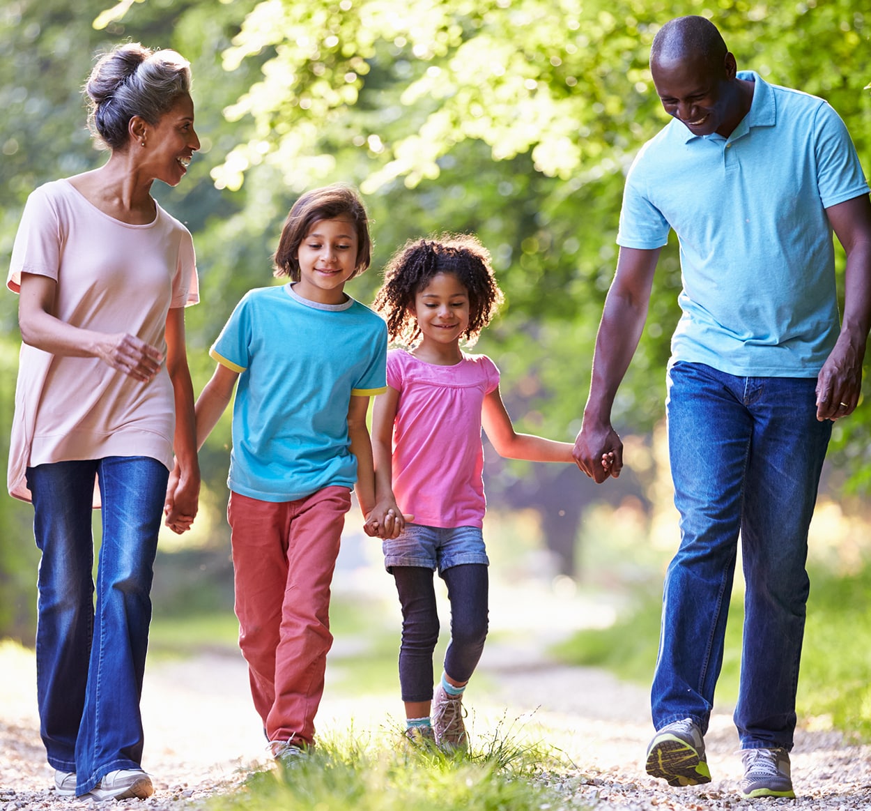 Un homme et une femme qui se tiennent les mains marchent dans la forêt avec leurs deux enfants, une fille et un garçon