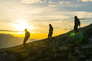 Trois personnes descendant une colline au coucher du soleil