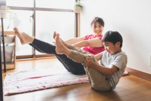 A mom and son doing yoga poses on a living room floor.