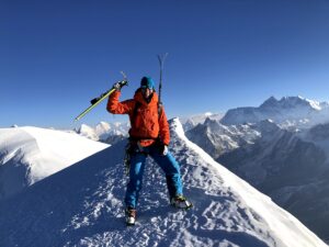 Jill Wheatley standing on Mera Peak (6,476 metres) in Nepal with Everest in the background while carrying skis and ski poles