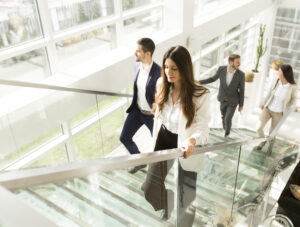 Four people in business attire walking up a set of stairs. 