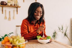 A smiling woman eating a salad