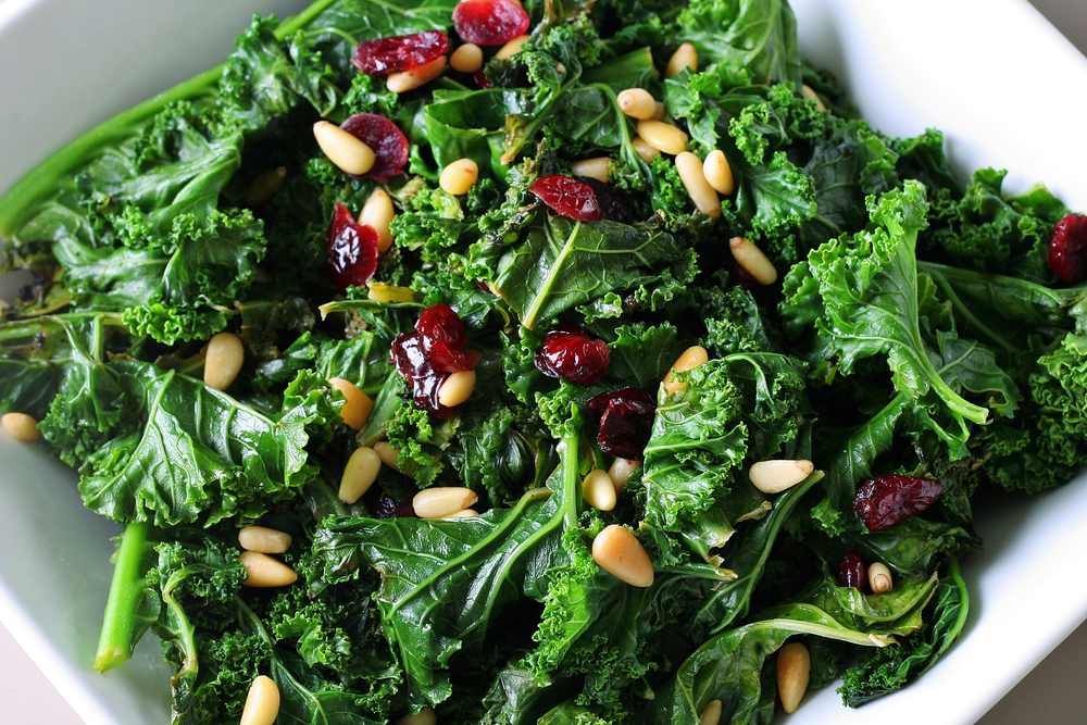 A kale salad topped with dried cranberries and seeds. 