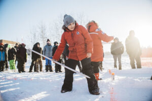 A boy playing the Dene game called snow snake, one of the sports featured at the Arctic Winter Games, in a snow-covered field. 